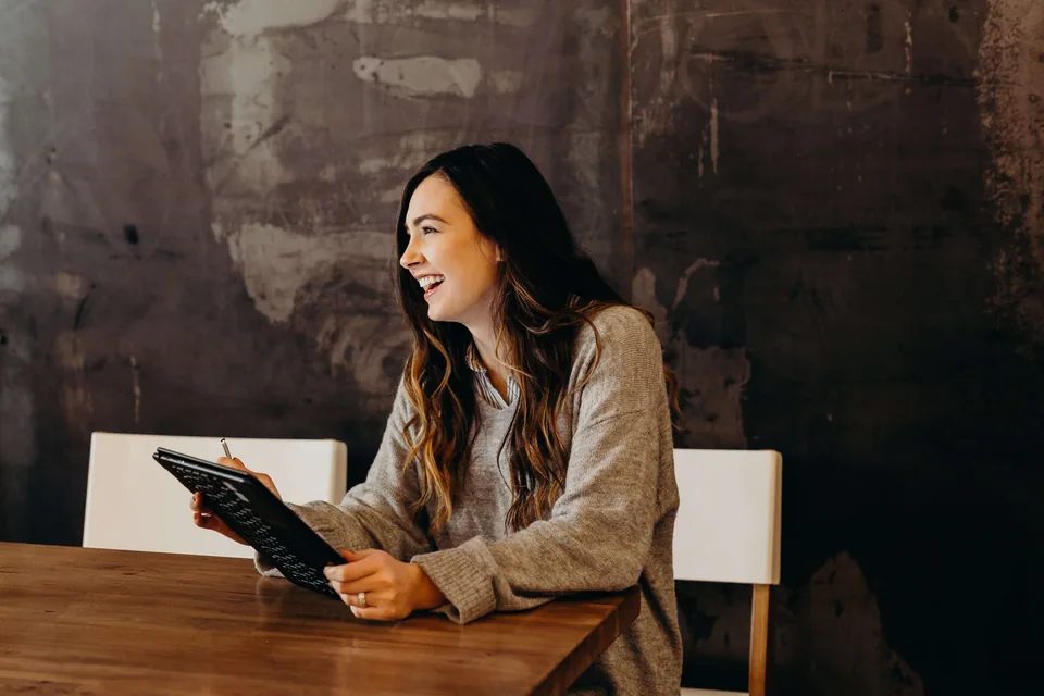 A woman holding a tablet and sitting on a cafe table.