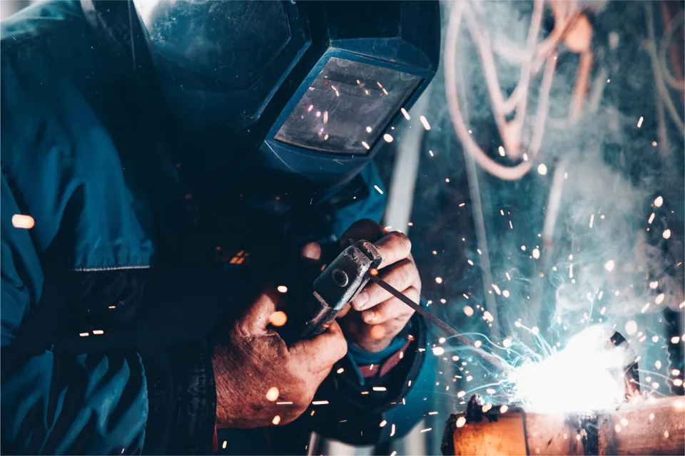 A man welding a type of metal with protective gear on.